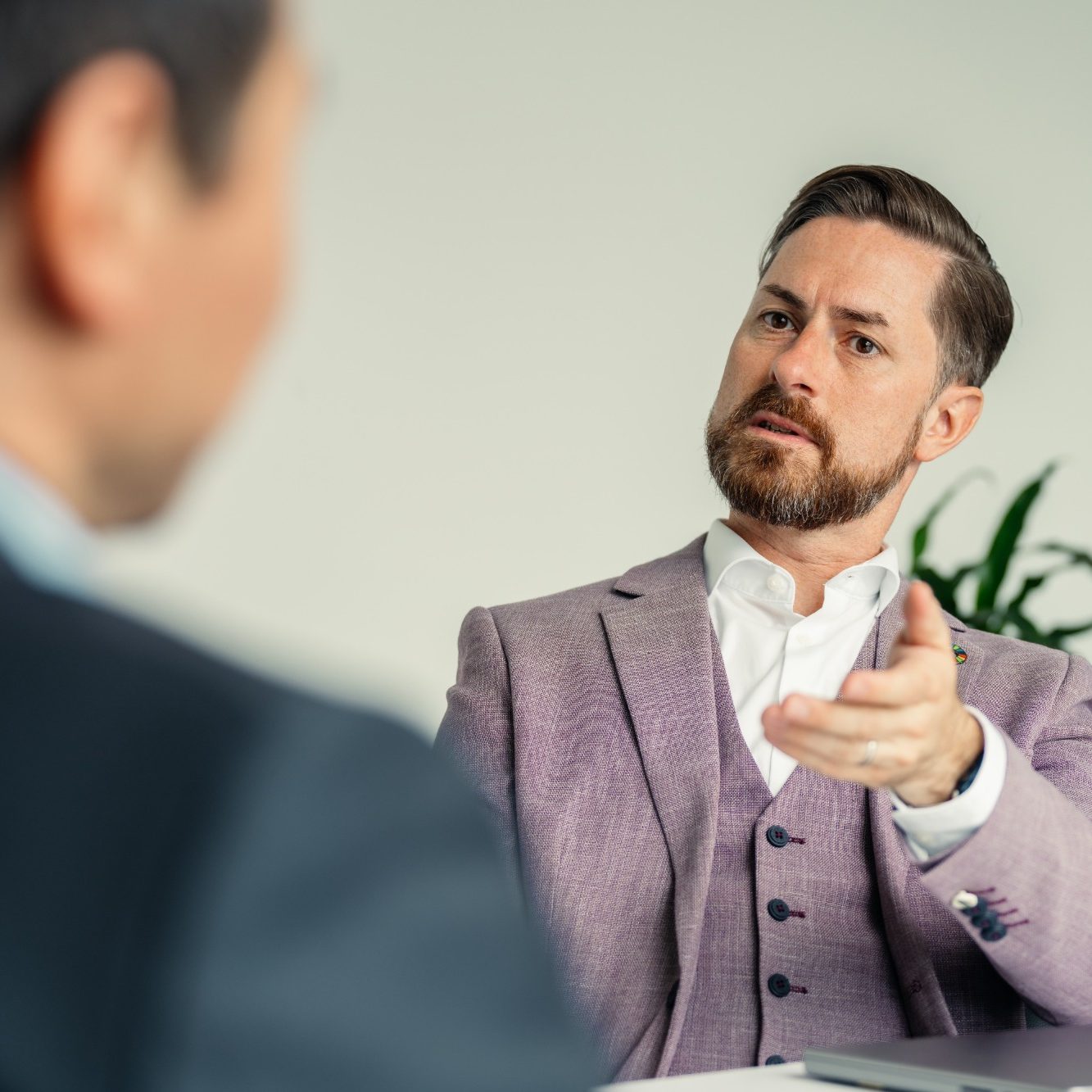 Ein Mann in einem Anzug spricht engagiert mit einem anderen Mann.